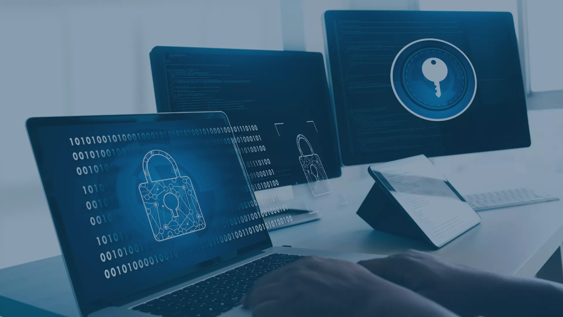Symbolische Darstellung eines sicheren IT-Betriebs: Laptop, Monitore und Tablet mit digitalen Schlössern, Schlüsseln und Binärcode visualisieren Schutz, Transparenz und Stabilität einer IT-Infrastruktur – sinnbildlich für ein maßgeschneidertes IT-Betriebskonzept von audius, das Prozesse, Verantwortlichkeiten und Standards für einen sicheren und effizienten IT-Betrieb definiert.
