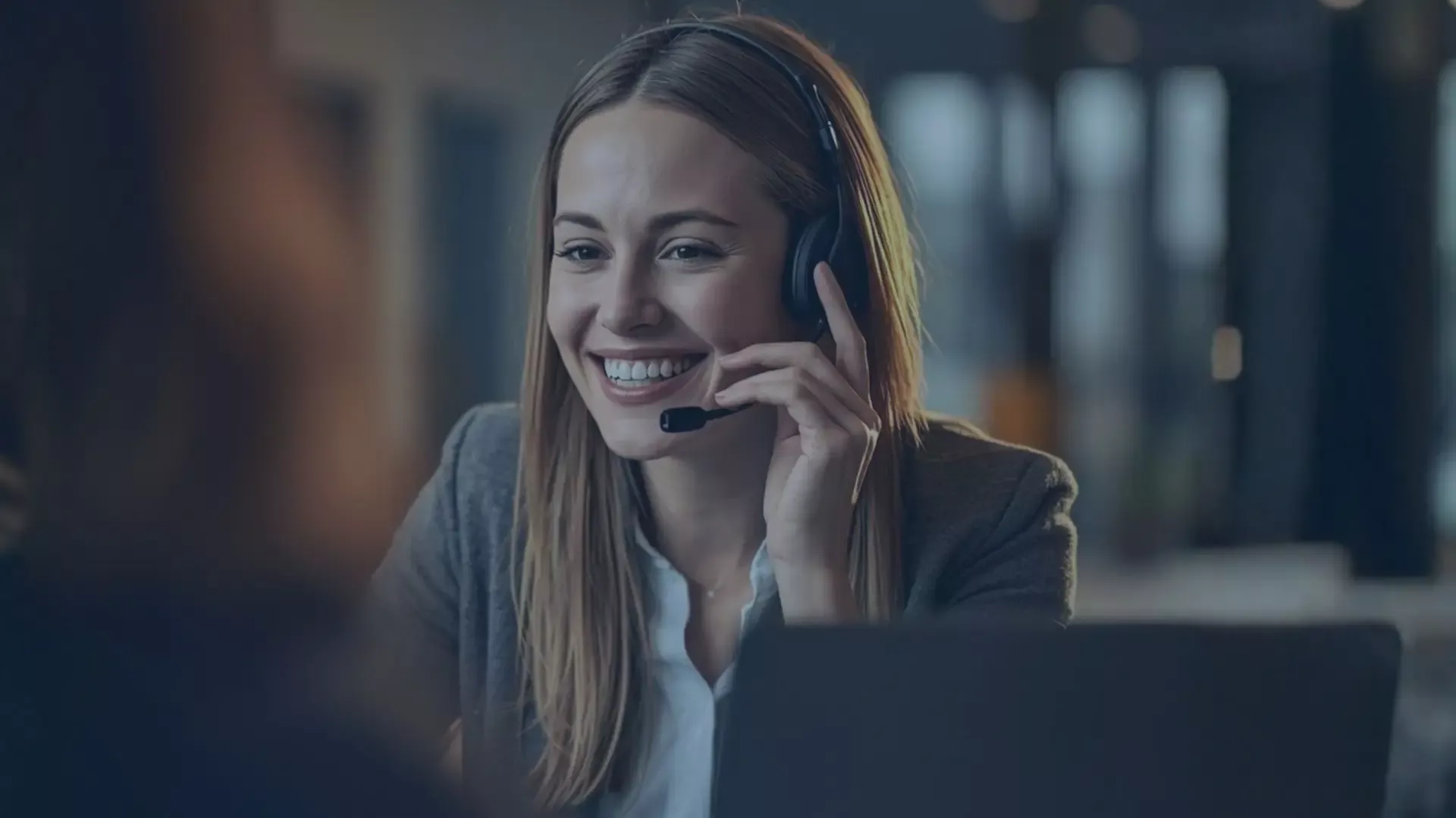 Headerbild mit einer telefonierenden Service-Mitarbeiterin in einem modernen Büro. Die Person wirkt freundlich und konzentriert, während sie mit einem Kunden spricht. Das Bild vermittelt professionelle, empathische Kommunikation und unterstreicht die Bedeutung von Soft Skills wie aktivem Zuhören und lösungsorientiertem Handeln im telefonischen Kundenservice.